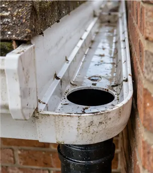 Cleared white gutter end and outlet above a black downpipe on a brick wall